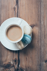 Cup of coffee and blue macaroons on wooden table background