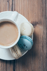 Cup of coffee and blue macaroons on wooden table background