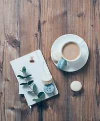 Cup of coffee and blue macaroons on wooden table background