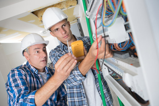 young apprentice with electrician professional