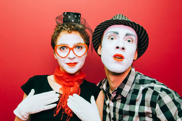 two mimes posing against a red wall background