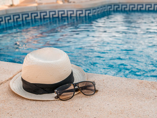 Hat and sunglasses at the pool. Summer holiday concept.
