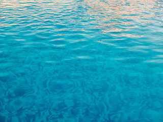 Ripple Water in swimming pool with sun reflection. Blue background colors.