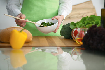 Closeup of human hands cooking vegetables salad in kitchen on the glass  table with reflection