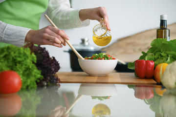 Closeup of human hands cooking vegetables salad in kitchen on the glass  table with reflection