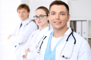 Fototapeta premium Cheerful smiling male doctor with medical staff at the hospital