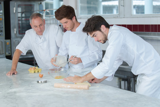 three bakers in bakery kneading fresh dough