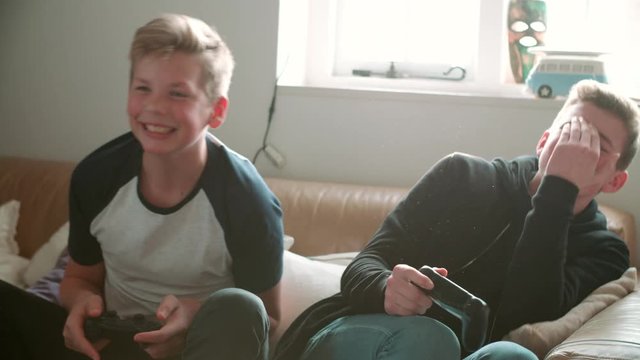 Two Teenage Boys Playing Video Game In Bedroom
