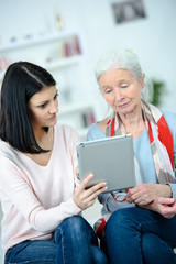 young woman helping her grandmother using a tablet