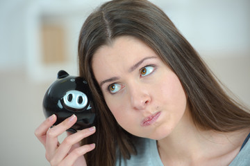 woman looking weird holding a piggy bank
