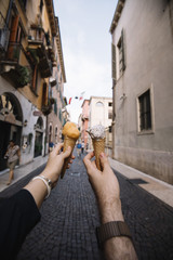Couple holding gelato ice-cream in their hands on the Italian city background