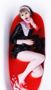 A woman nun is lying in the bathroom in the blood. Halloween costume. The monk is a vampire girl, a demon.