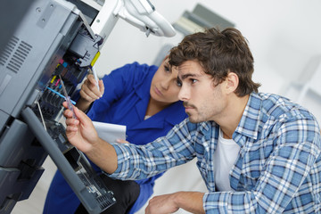 Naklejka na ściany i meble two young technicians repairing printer