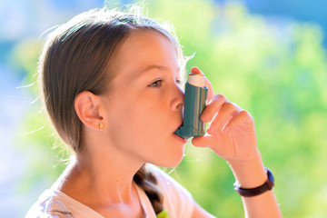 Girl using asthma inhaler in a park