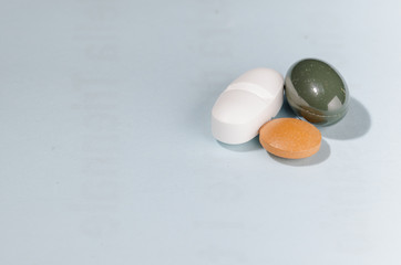 group of three pills over a pale blue background with copys space on the left. pharmaceutical. disease. cure. medicine