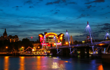 Fototapeta premium The Charing Cross station and Hungerford Bridge by the River Thames at night.