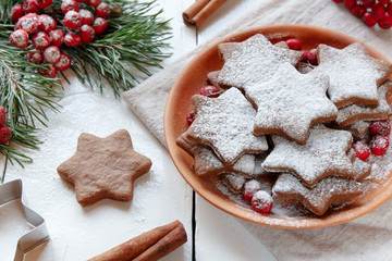 Traditional Christmas gingerbread cookies, stars in powdered sugar on the plate. Berries of red Rowan branch spruce.