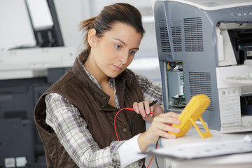 handywoman checking computer with a multimeter