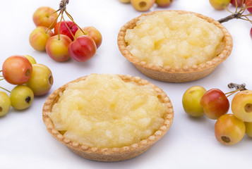 Still life. Two cakes with apple jam, bunches of small apples on a white background