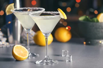 Muurstickers Bril met smakelijke lemon drop martini cocktail op tafel © Africa Studio