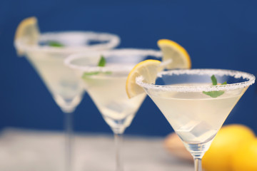 Glass with tasty lemon drop martini cocktail on blurred background, closeup