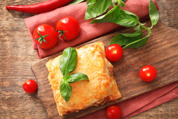 Portion of tasty lasagna on wooden board