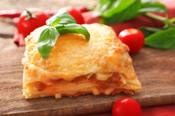 Portion of tasty lasagna on wooden board