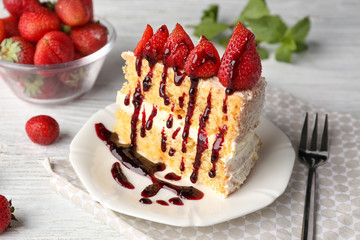 Delicious cake served with strawberries and syrup on plate