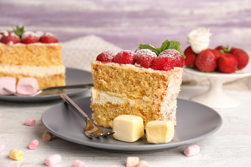 Slice of delicious cake decorated with strawberries on plate