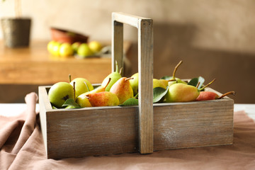 Ripe pears in wooden basket on table indoors
