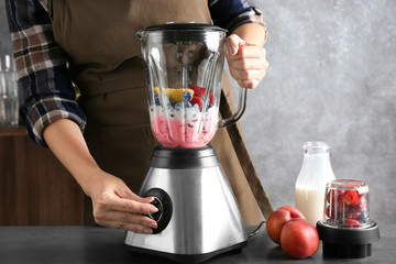 Young woman preparing smoothie in kitchen