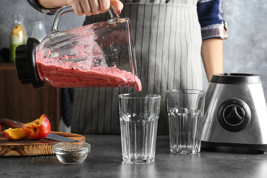 Young woman preparing smoothie with chia seeds on table in kitchen