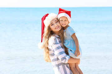Obraz premium Young mother with cute girl on beach. Christmas celebration concept
