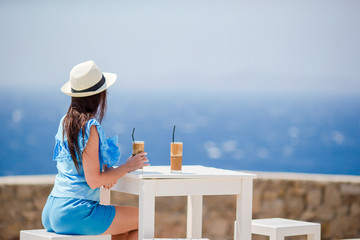 Young in outdoor cafe enjoying sea view. Beautiful woman relax during exotic vacation on the beach...