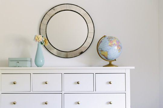 Flower vase, globe and jewelry box on cabinet against wall