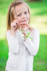 Portrait of adorable little girl in blooming apple tree garden on spring day