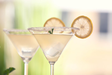 Glasses with tasty lemon drop martini cocktail on blurred background, closeup