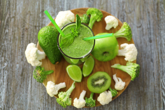 Healthy smoothie with kale in glass on wooden board