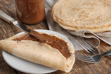Delicious crepe with chocolate sauce on wooden table