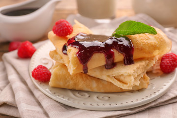 Delicious pancakes with raspberry jam on table
