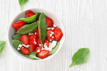 Plate of salad with spinach, strawberry and cottage cheese on table