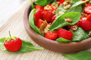Plate of salad with spinach, strawberry and walnuts on table, closeup