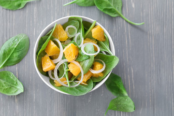 Salad with spinach and orange in bowl on table