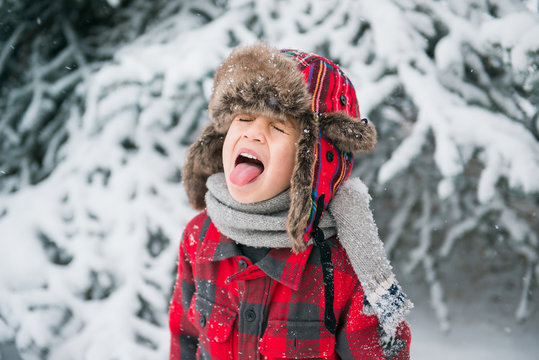 child sticks tongue out to catch falling snowflakes