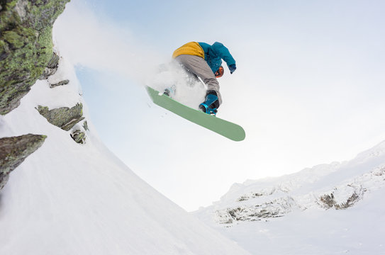 Snowboarder jumping off a cliff in winter