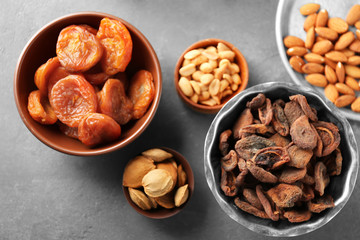 Dried apricots and nuts in different dishes on table