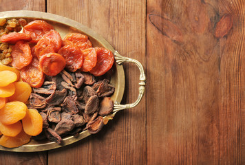 Tray with dried apricots and raisins on wooden background