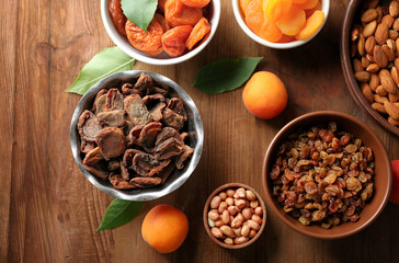 Dried apricots, raisins and nuts in different dishes on wooden table