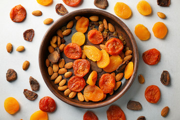 Plate with dried apricots, raisins and nuts on white background