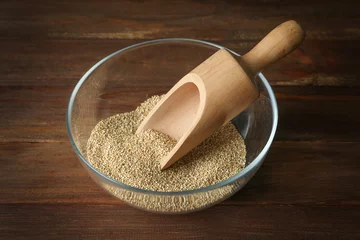 Wandaufkleber Bowl with raw quinoa grains on wooden background © Africa Studio